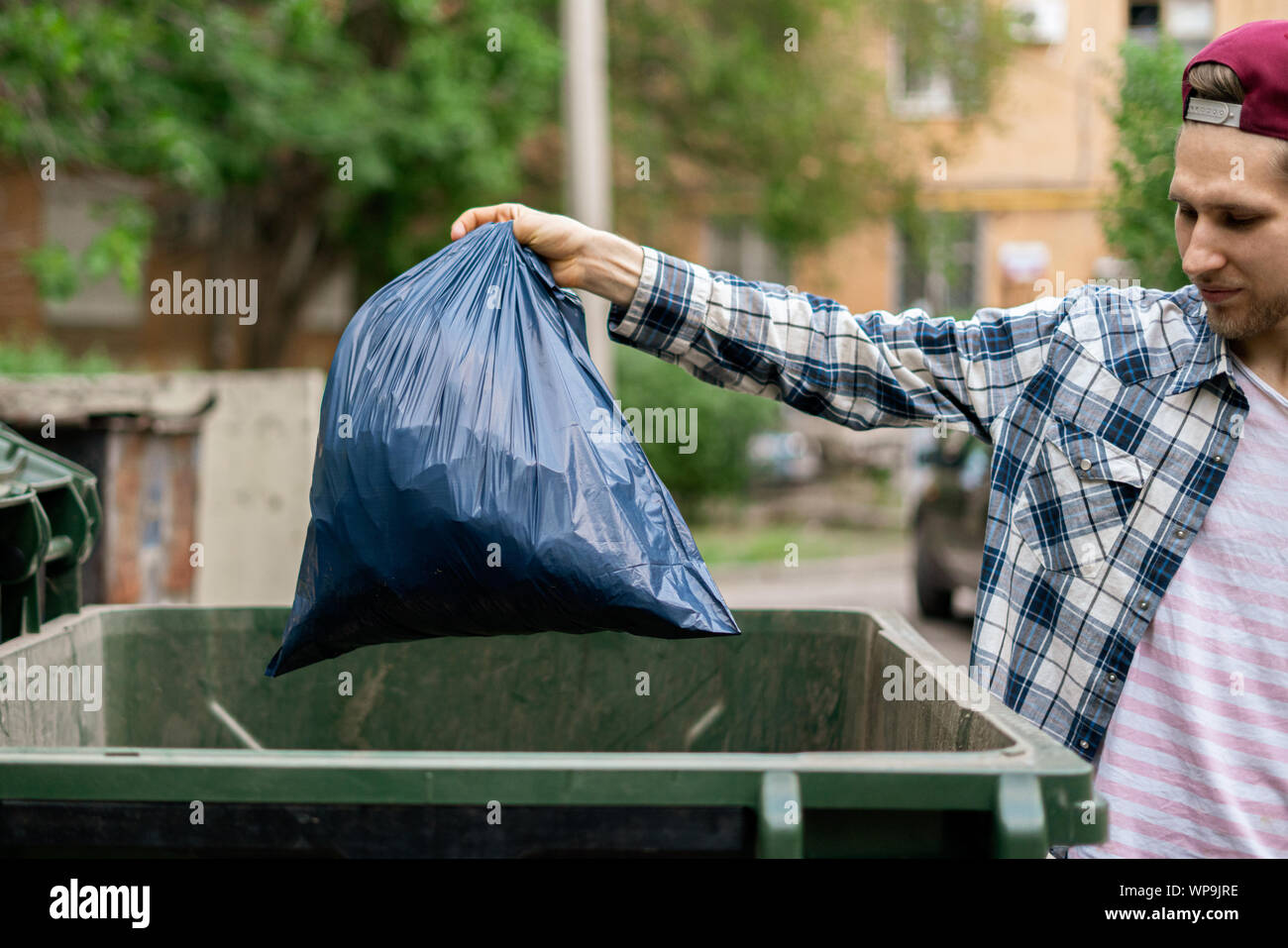 male dumping waste package into a big trash bin containers Stock Photo
