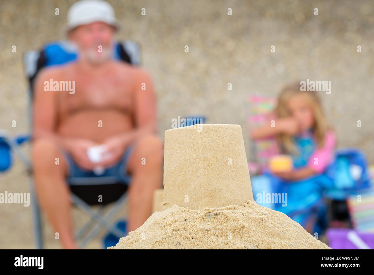 A man and girl behind a sandcastle on a beach. Stock Photo