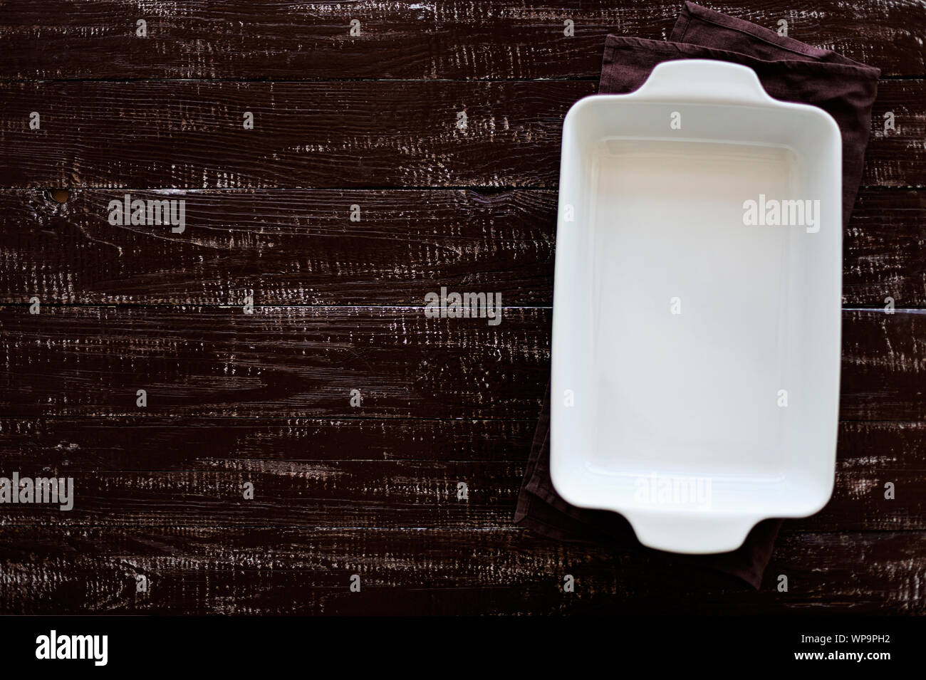 Ceramic white baking dish on a wooden old background. Selective focus. Stock Photo