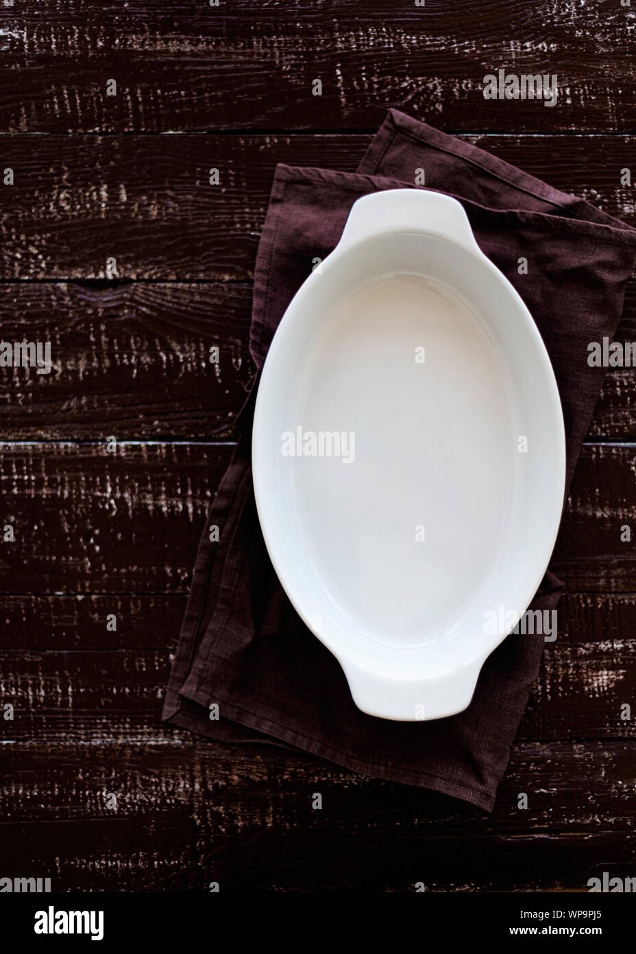Ceramic white baking dish on a wooden old background. Selective focus. Stock Photo