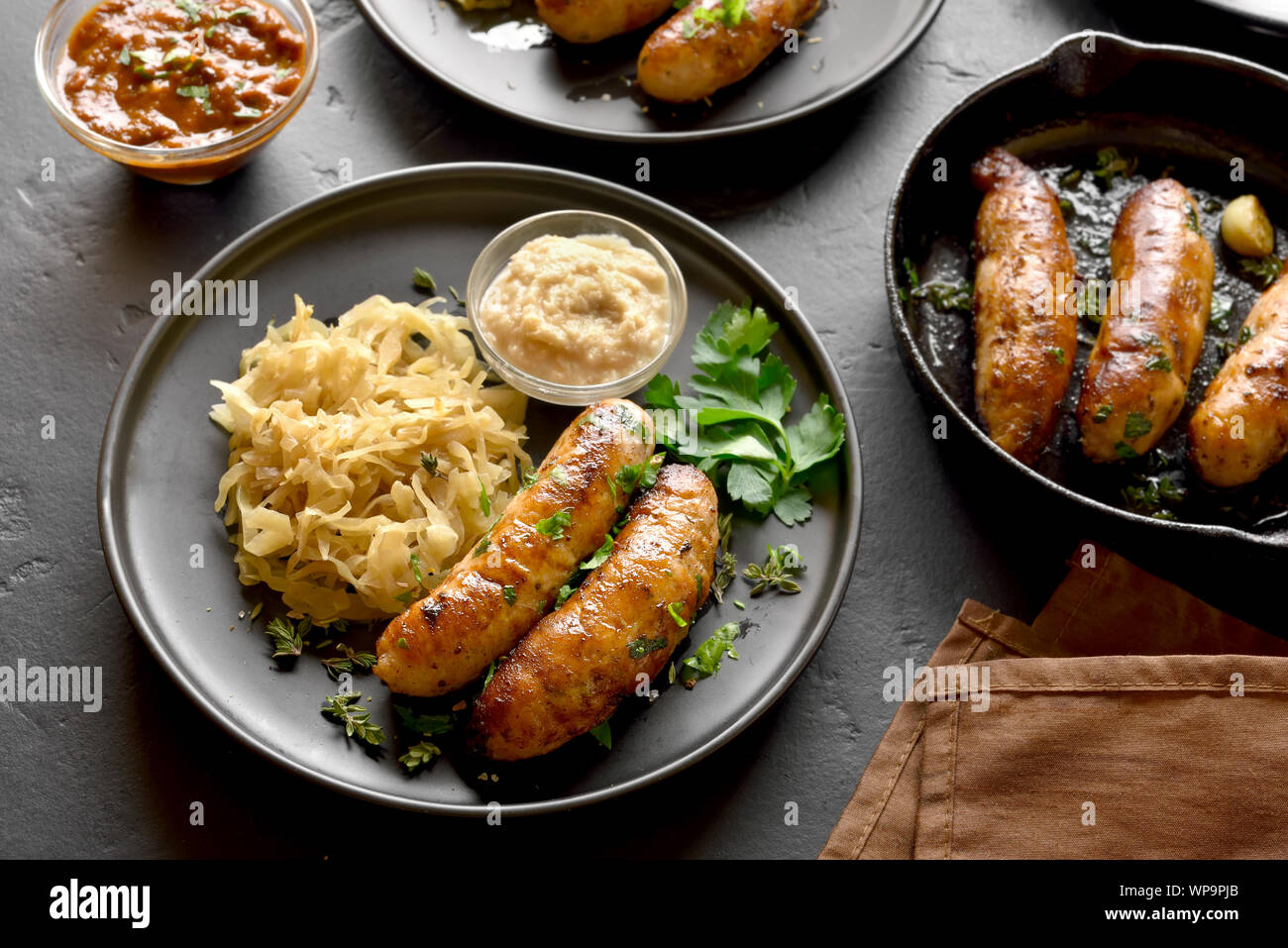 Grilled sausages with stewed sauerkraut and horseradish on plate over ...