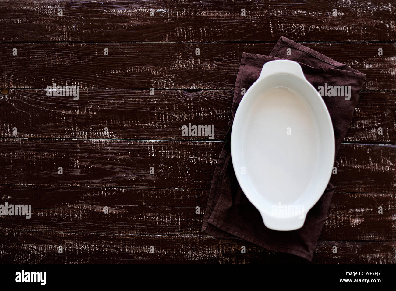 Ceramic white baking dish on a wooden old background. Selective focus. Stock Photo