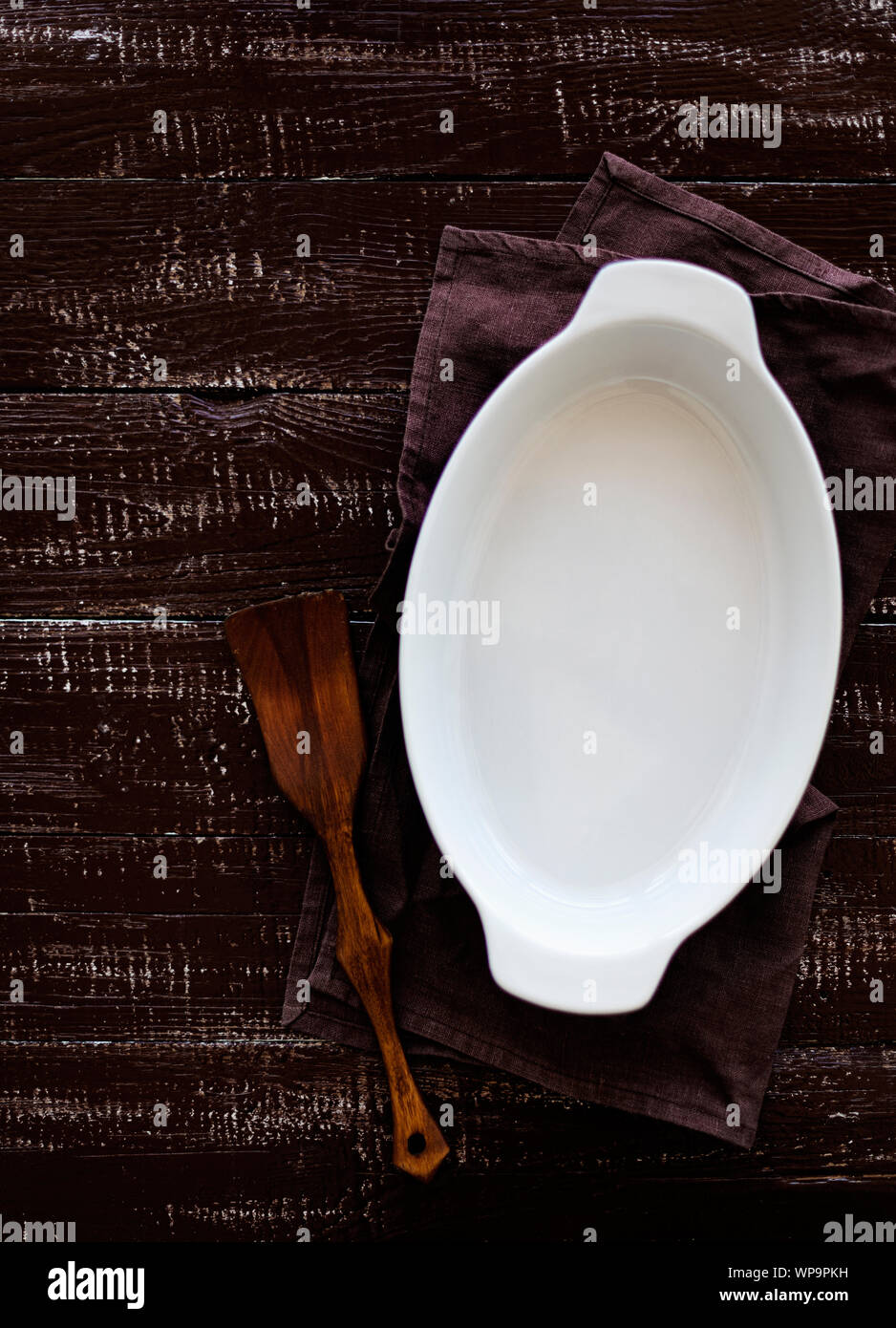 Ceramic white baking dish on a wooden old background. Selective focus. Stock Photo