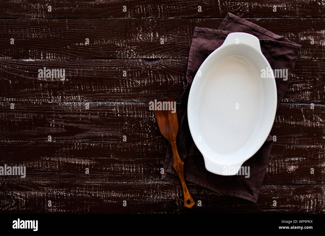 Ceramic white baking dish on a wooden old background. Selective focus. Stock Photo