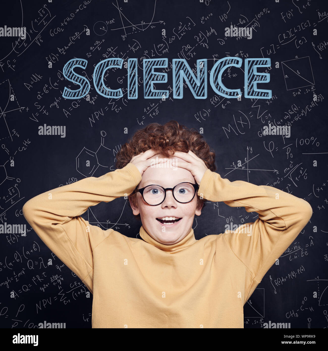 Happy little boy student against blackboard with science and maths formulas Stock Photo