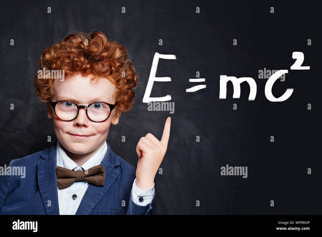 Confident child student on blackboard background pointing at science formula Stock Photo