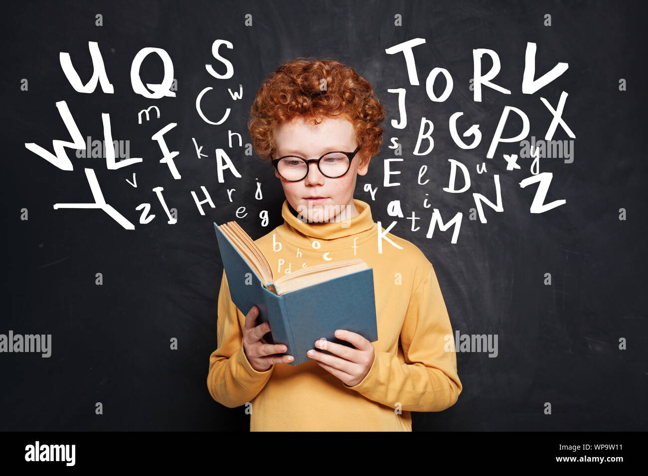 Child reading. Kid school boy holding book on black background Stock Photo
