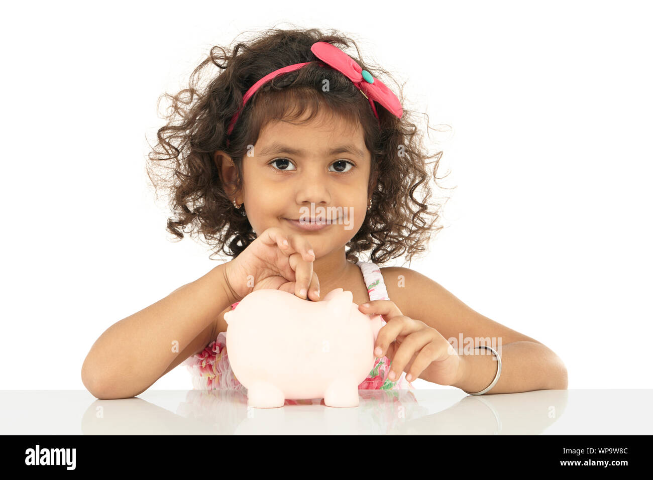 Girl inserting coin into a piggy bank Stock Photo - Alamy