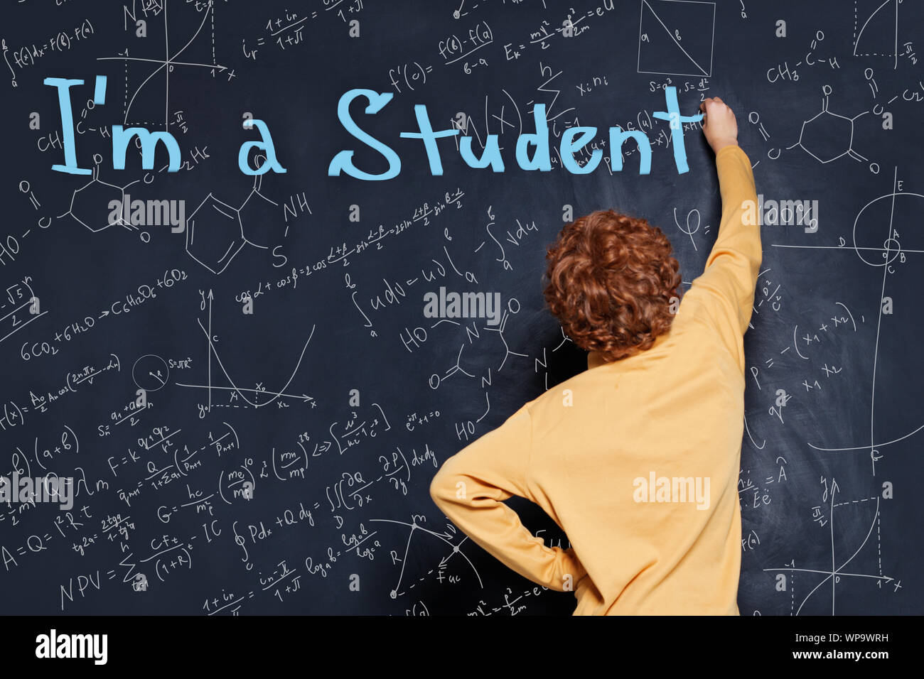 Back to school concept. Happy child student writing on blackboard background Stock Photo