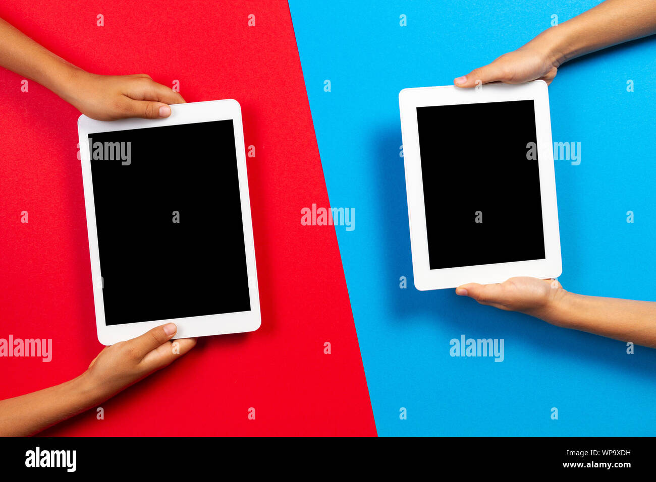 Kids holding tablet computer over red and light blue background Stock Photo