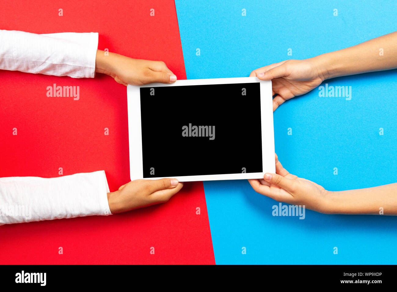 Kids holding tablet computer over red and light blue background Stock Photo
