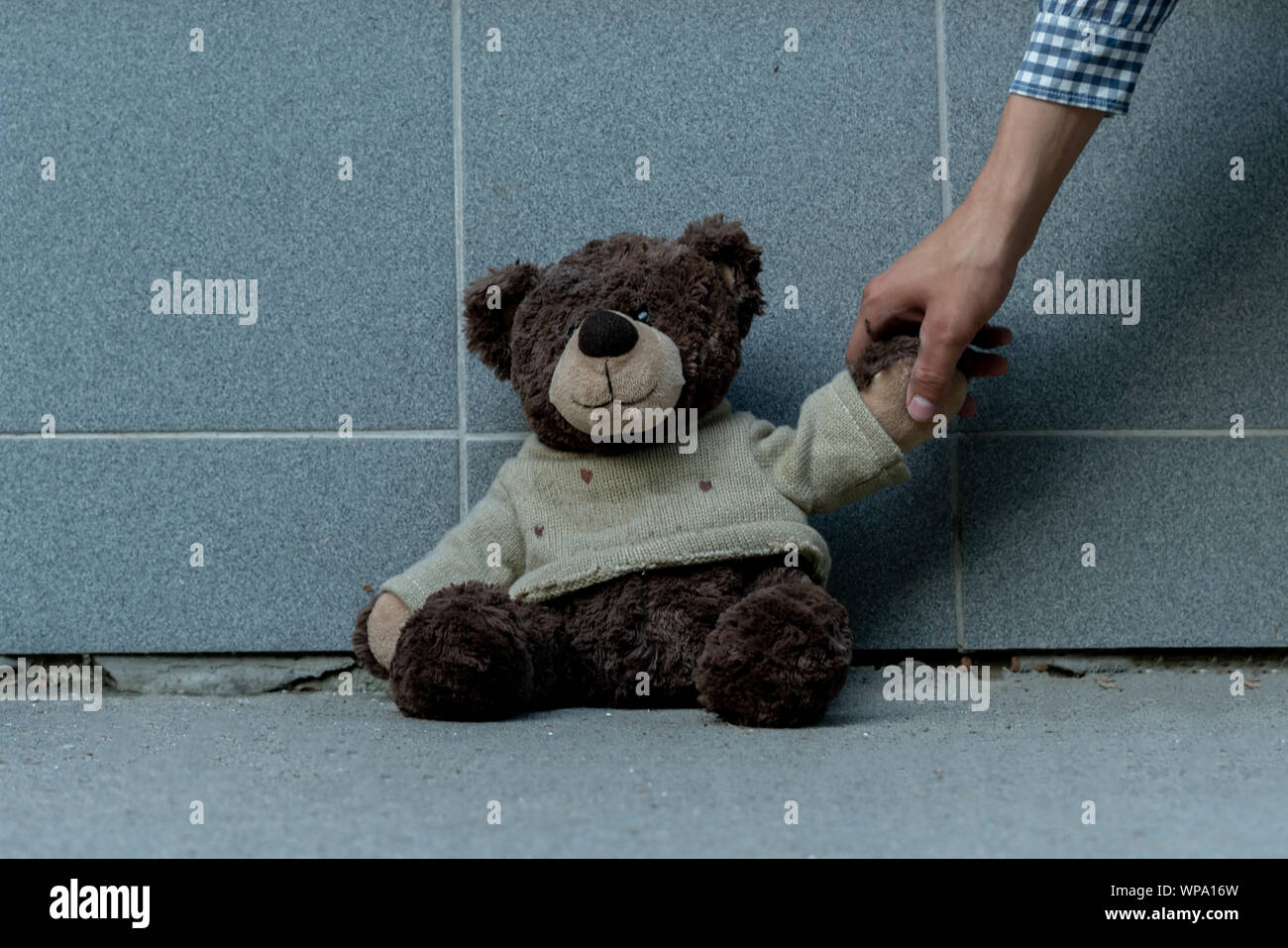 human hand grab the dirty teddy bear from the ground outdoors, lost concepts Stock Photo