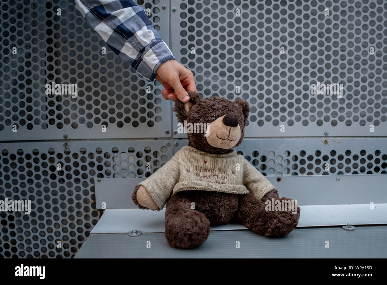 human hand grab the dirty teddy bear from the ground outdoors, lost concepts Stock Photo