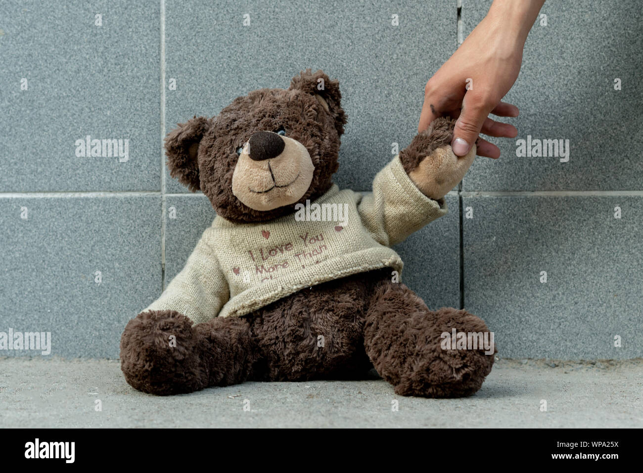 human hand grab the dirty teddy bear from the ground outdoors, lost concepts Stock Photo