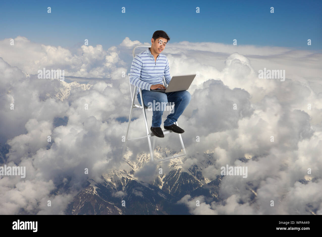 Young man sitting on a step ladder using a laptop Stock Photo