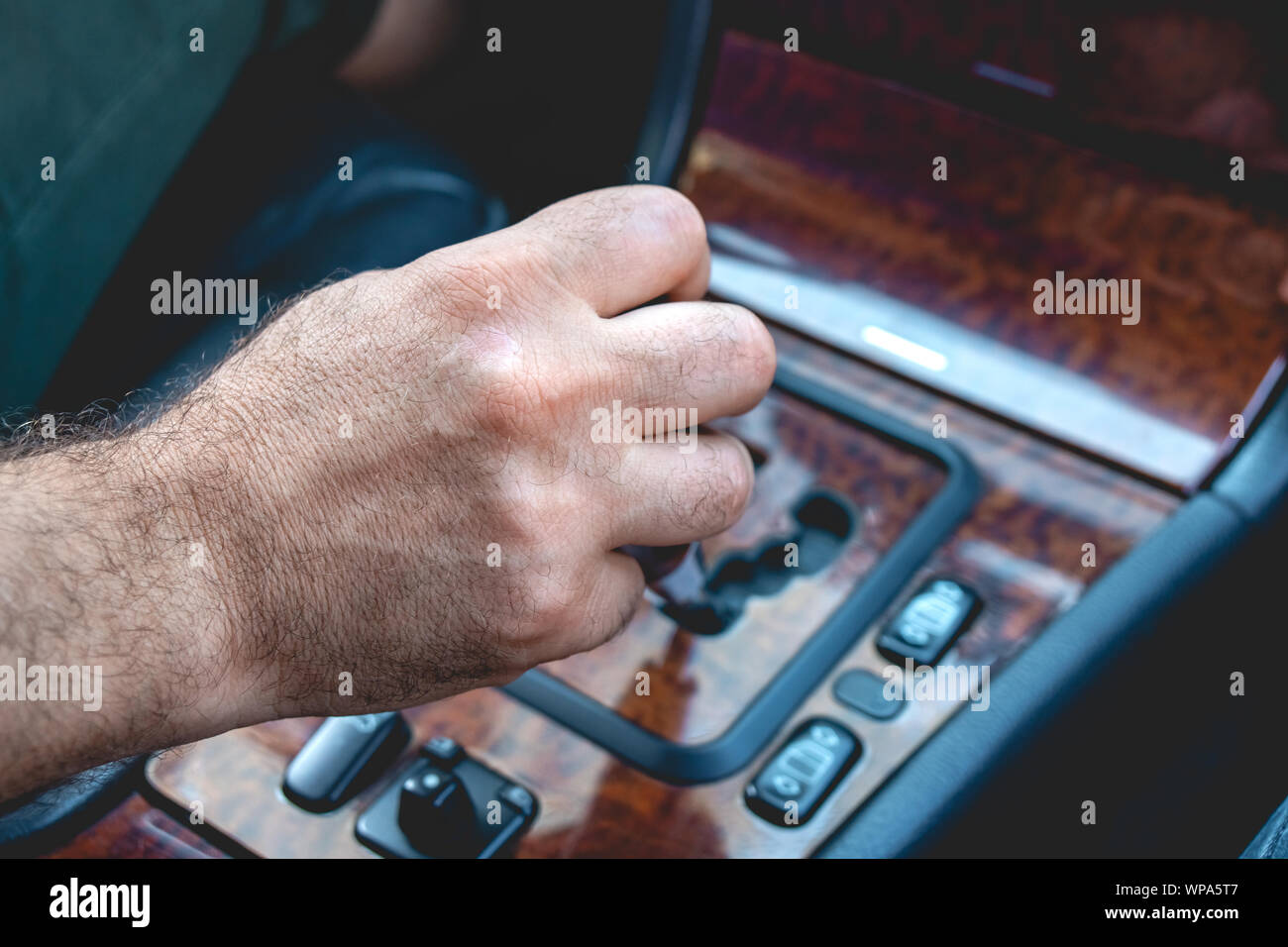 Driver man hand holding automatic transmission in car. Male hand