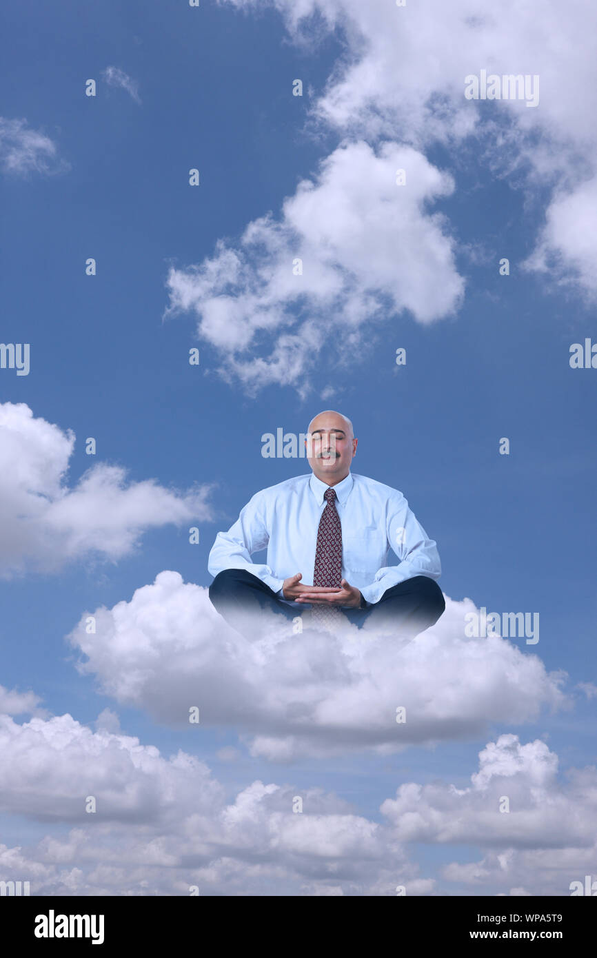 Businessman sitting on clouds practicing yoga Stock Photo