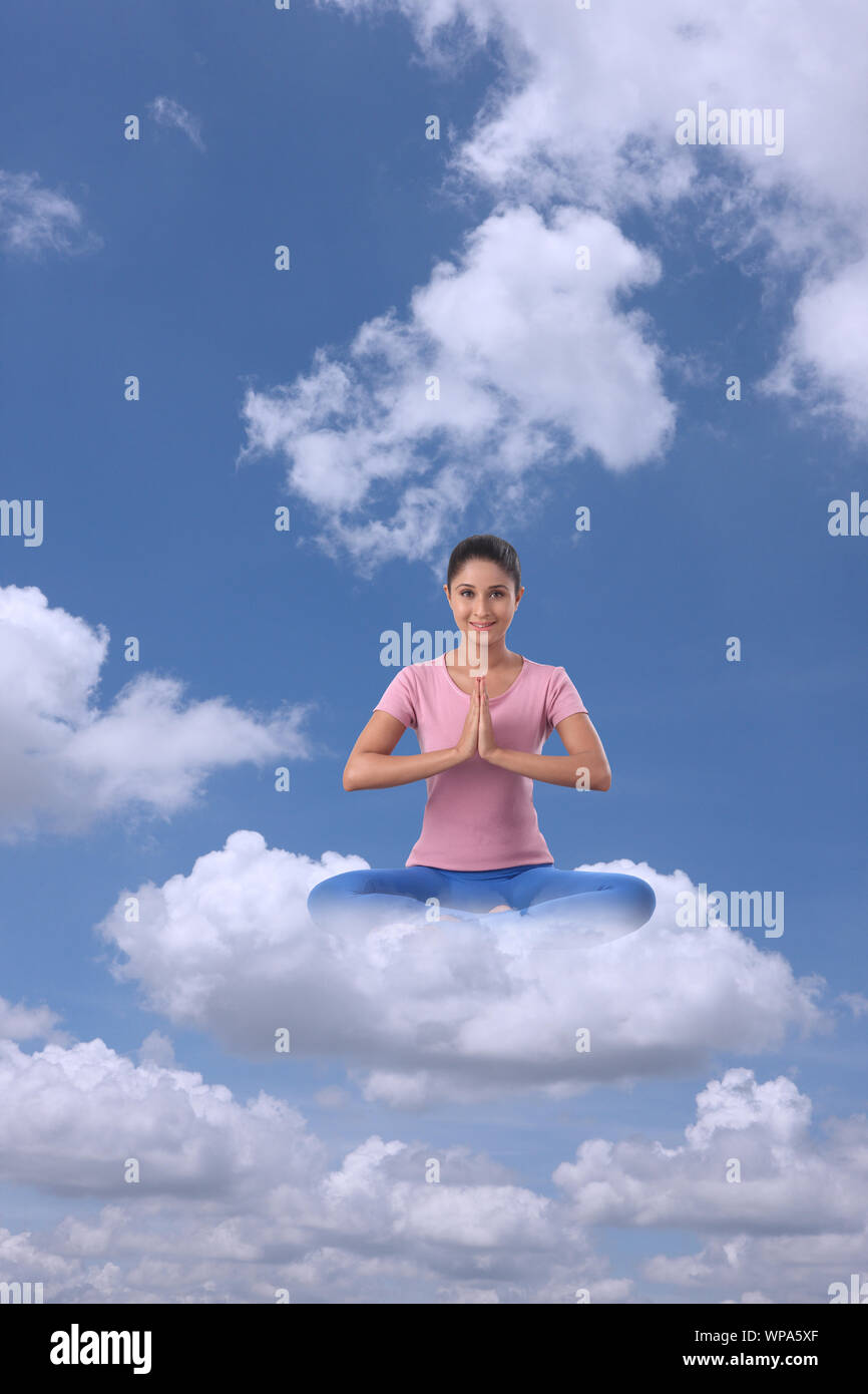 Young woman sitting on clouds practicing yoga Stock Photo