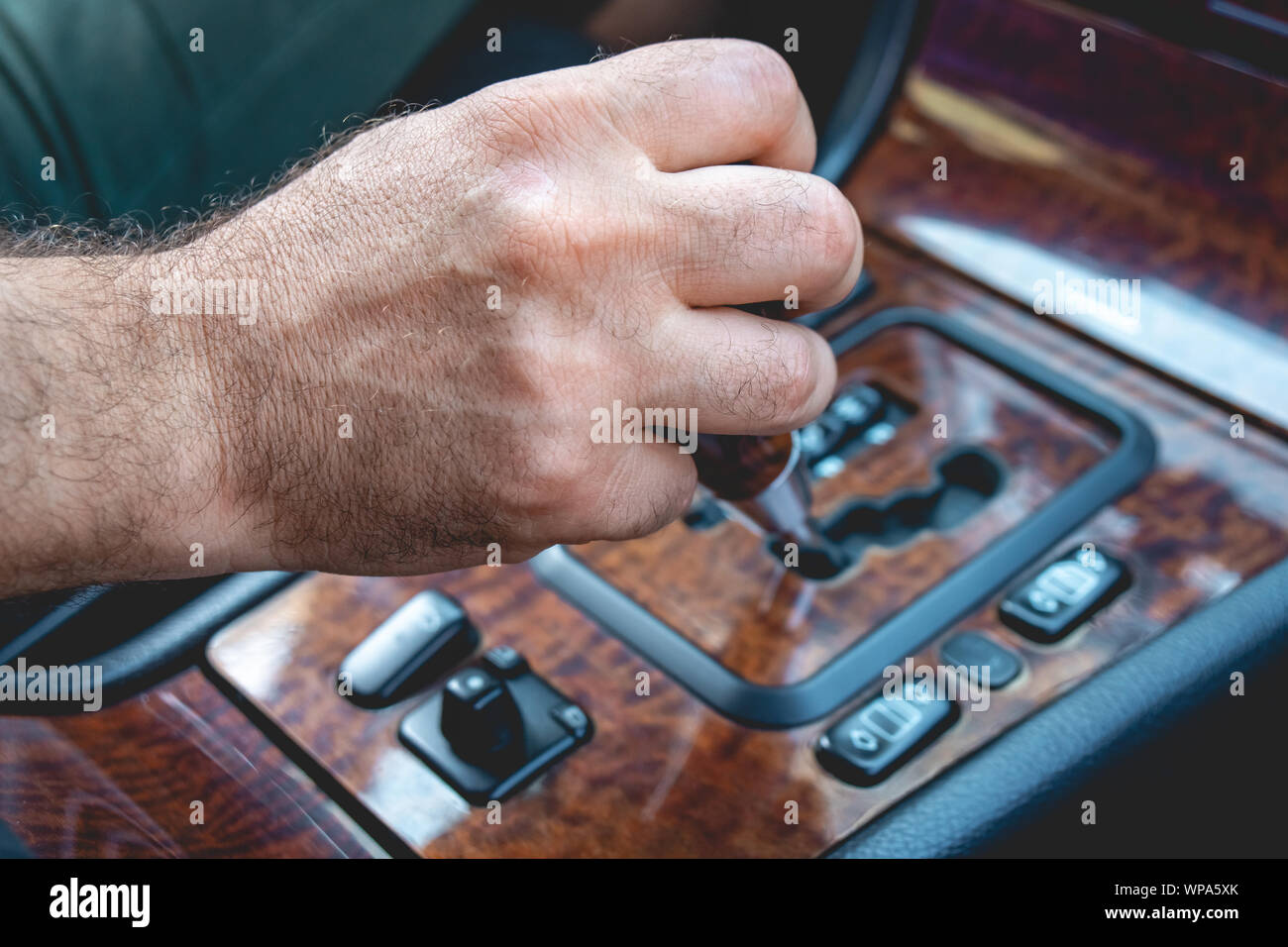 Driver man hand holding automatic transmission in car. Male hand
