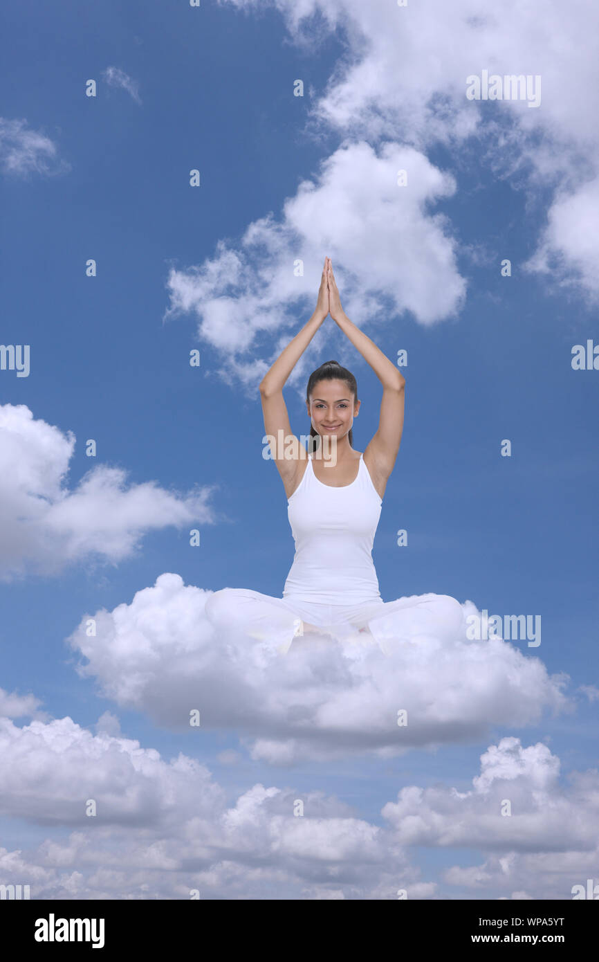 Young woman sitting on clouds practicing yoga Stock Photo