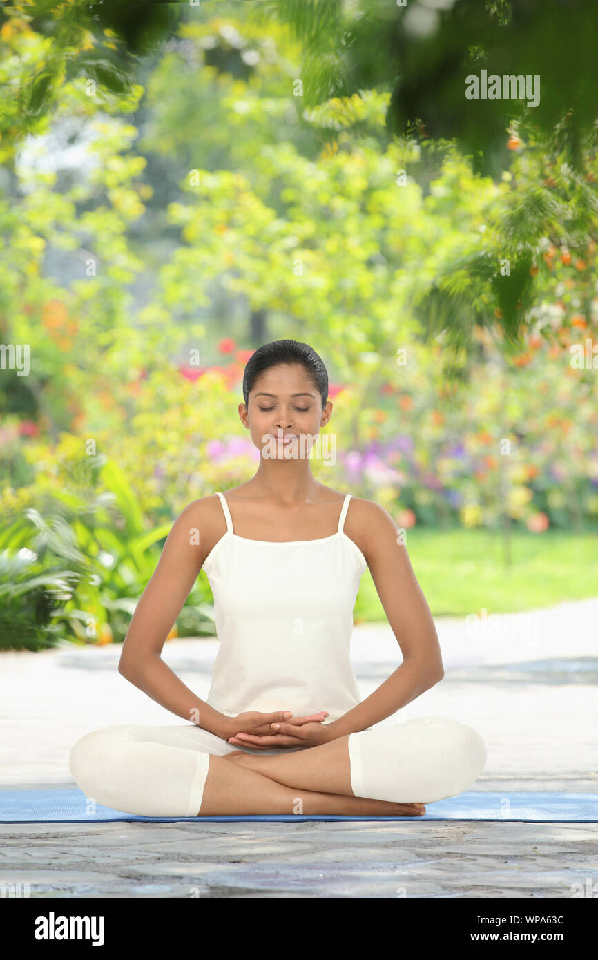 Young woman practicing yoga in a lawn Stock Photo