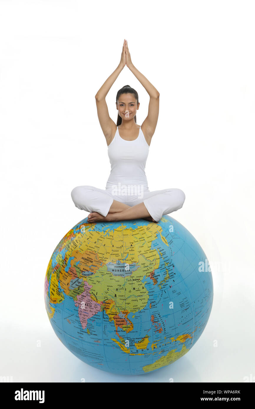 Young woman practicing yoga on a globe Stock Photo