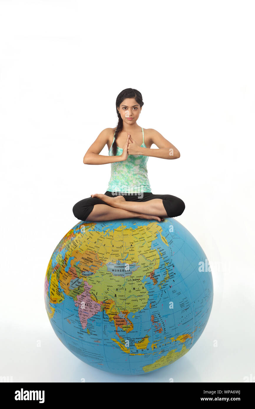 Young woman practicing yoga on globe Stock Photo