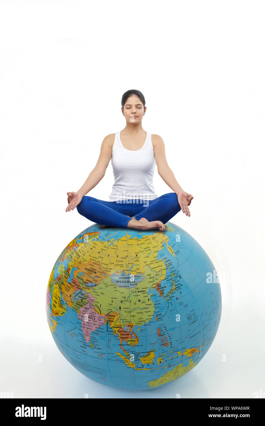 Young woman practicing yoga on a globe Stock Photo