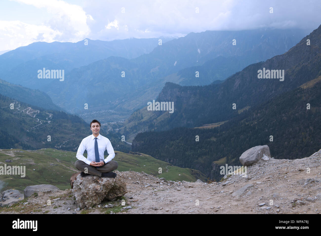 Businessman practicing yoga in a valley Stock Photo