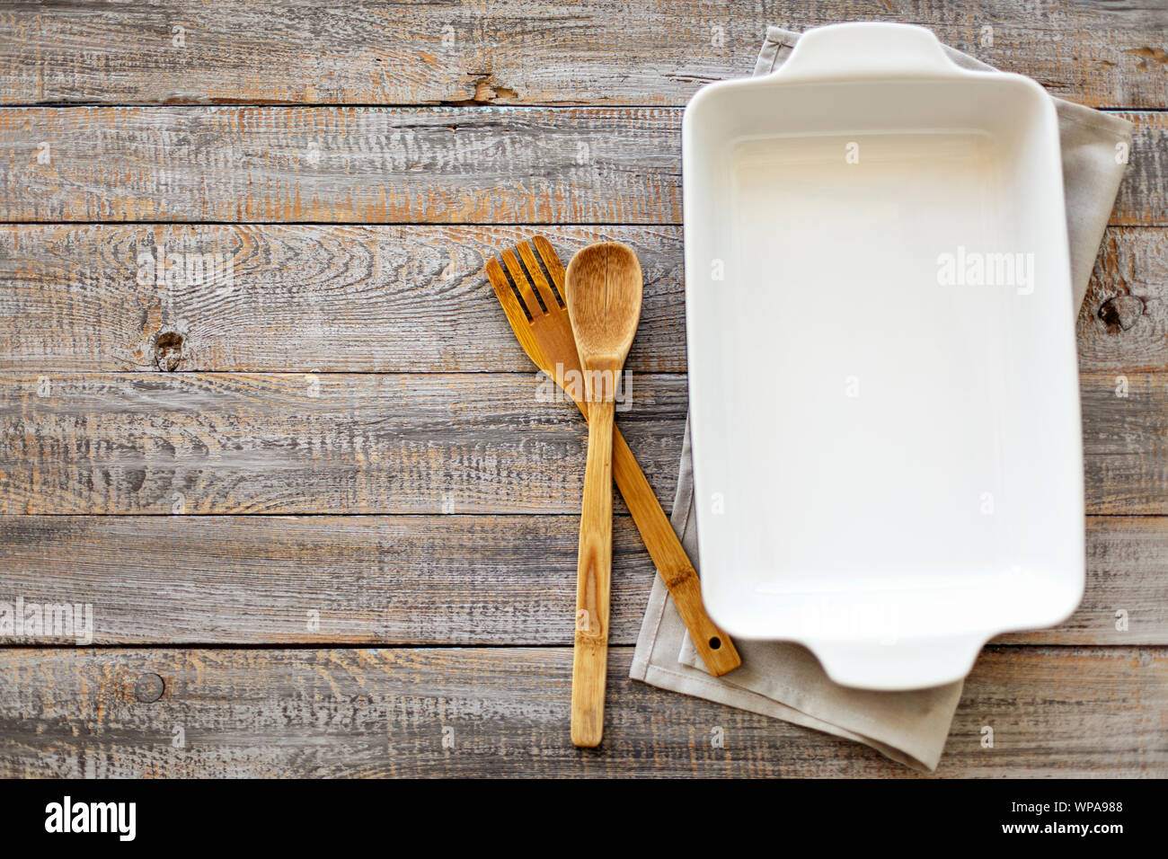 Ceramic white baking dish on a wooden old background. Selective focus. Stock Photo