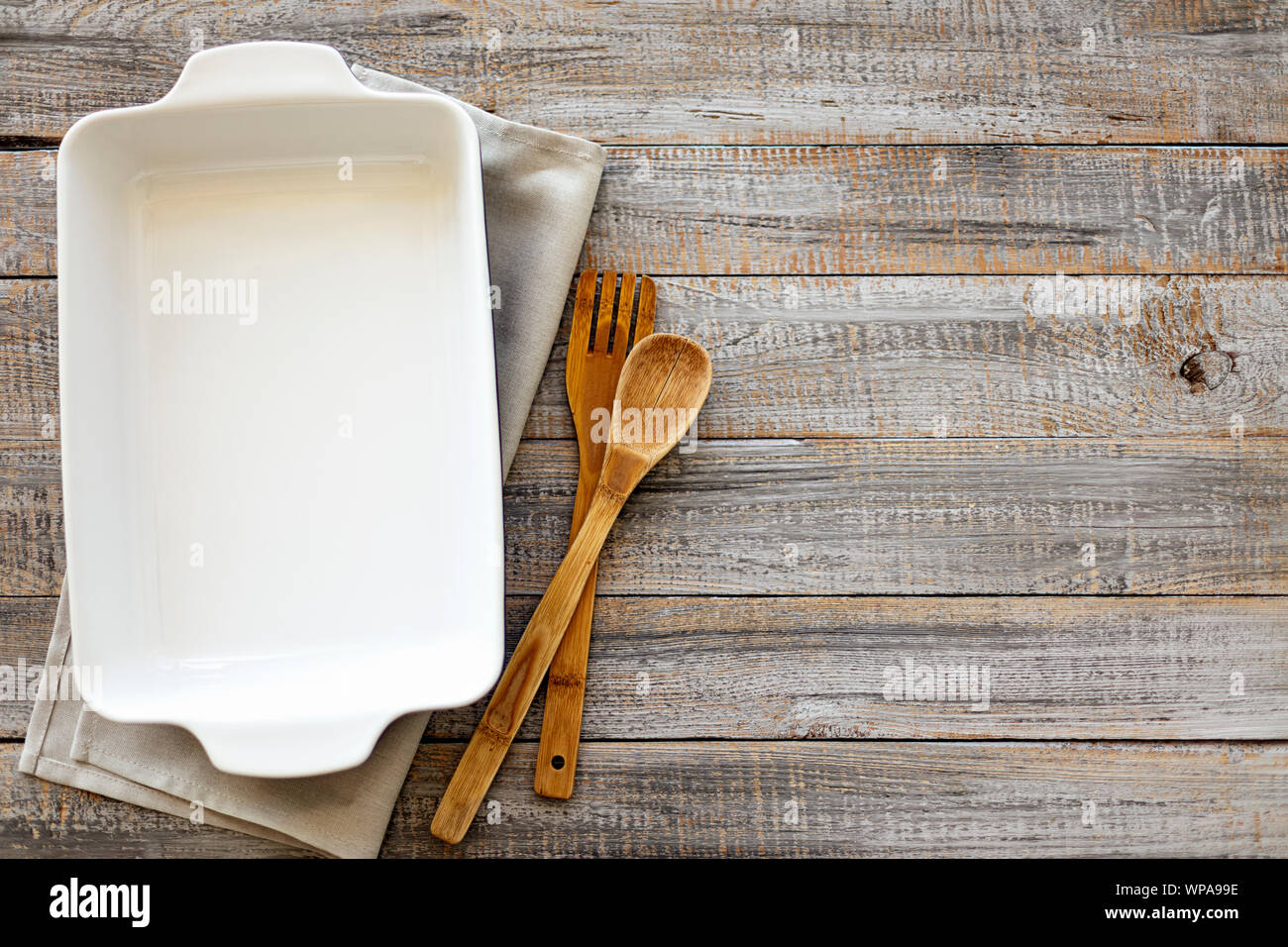Ceramic white baking dish on a wooden old background. Selective focus. Stock Photo
