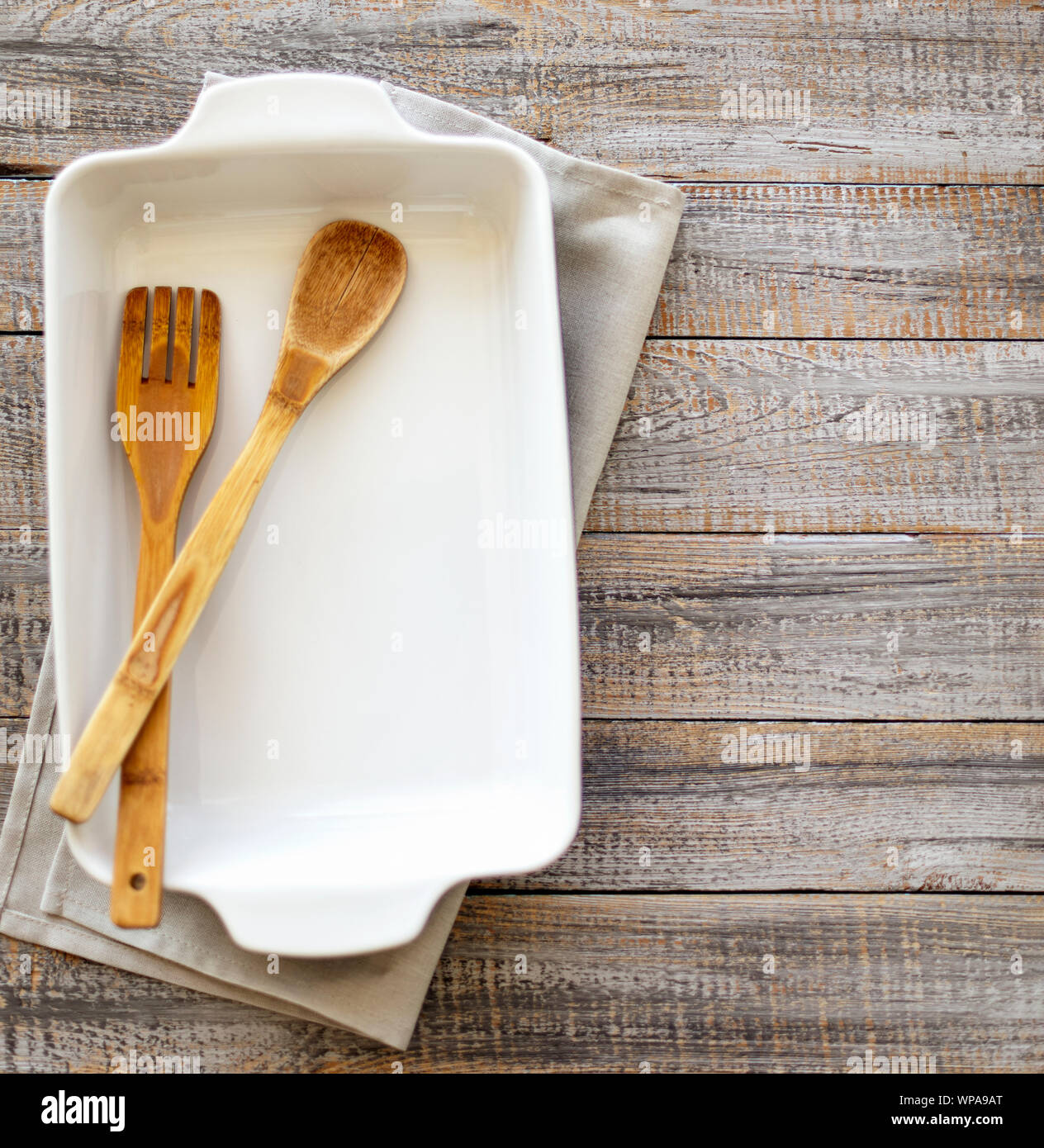 Ceramic white baking dish on a wooden old background. Selective focus. Stock Photo