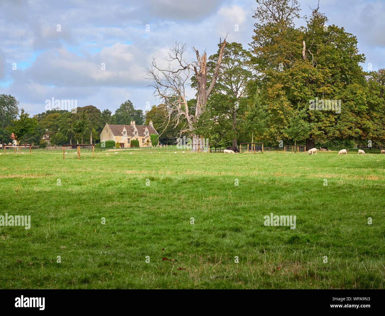 A stone cottage in the grounds of Culverthorpe hall in lincolnshire with trees and grassland in the foreground Stock Photo