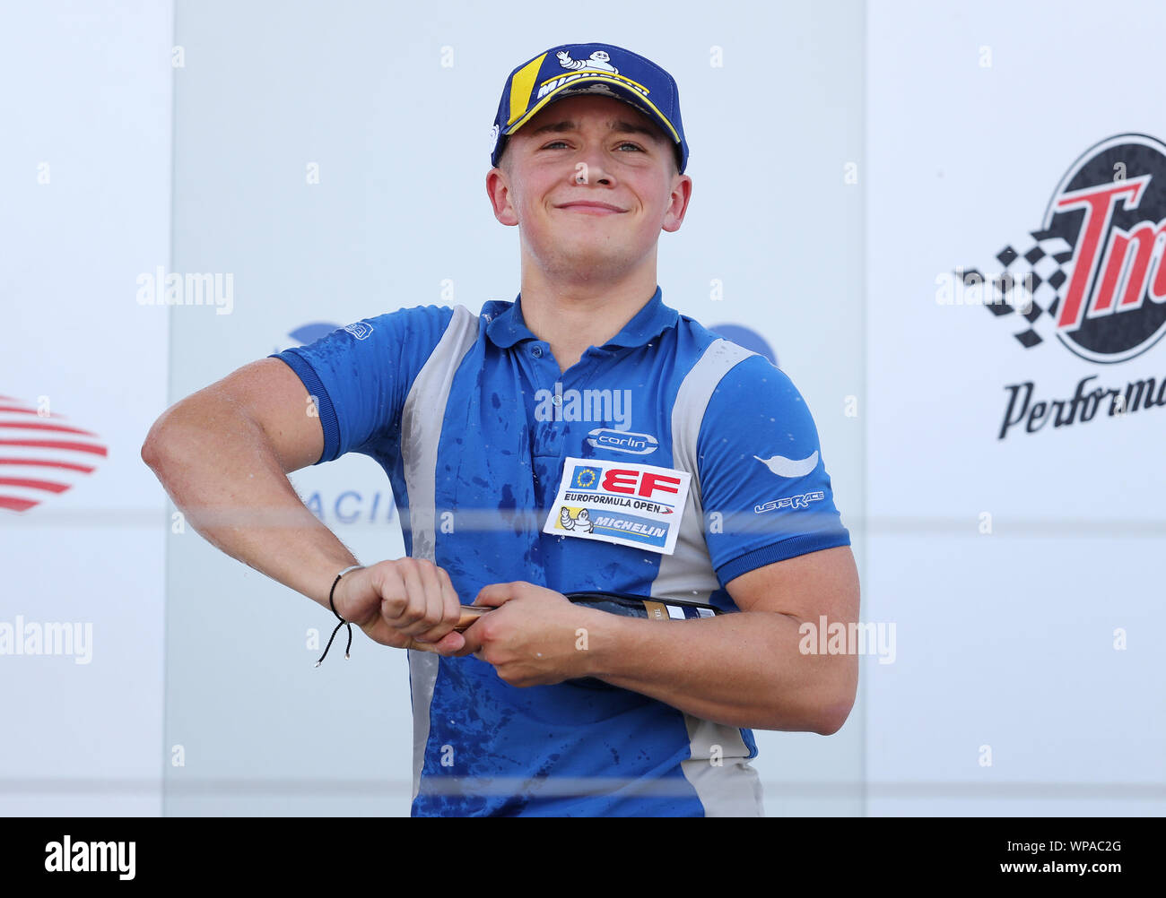 Carlin Motorsport's Billy Monger struggles to open the champagne after finishing third in the rookie race 2 of the Euroformula Open at Silverstone, Towcester. Stock Photo