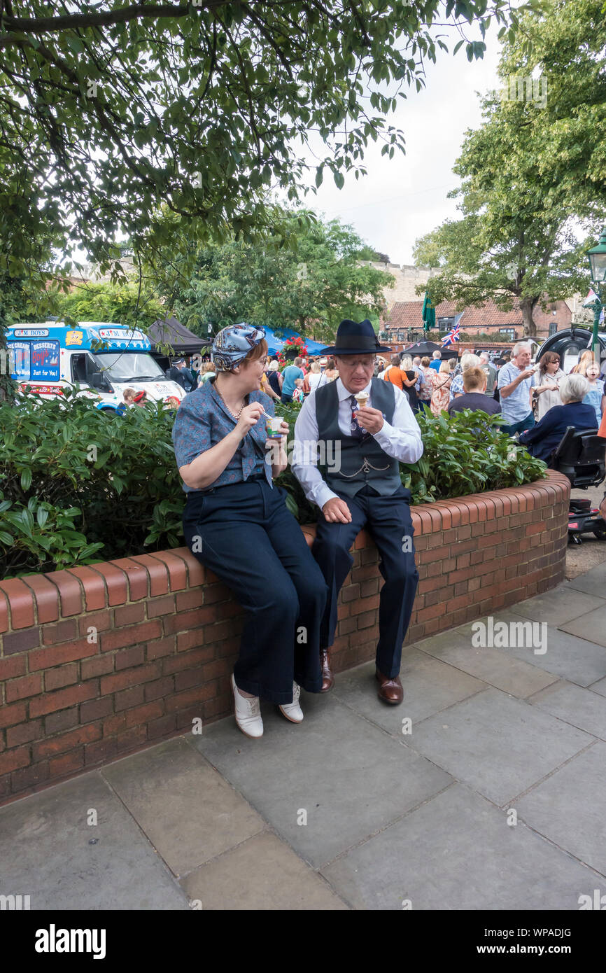 Couple in 1940's costume sat on wall enjoying break Lincoln 1940's weekend Lincolnshire 2019 Stock Photo