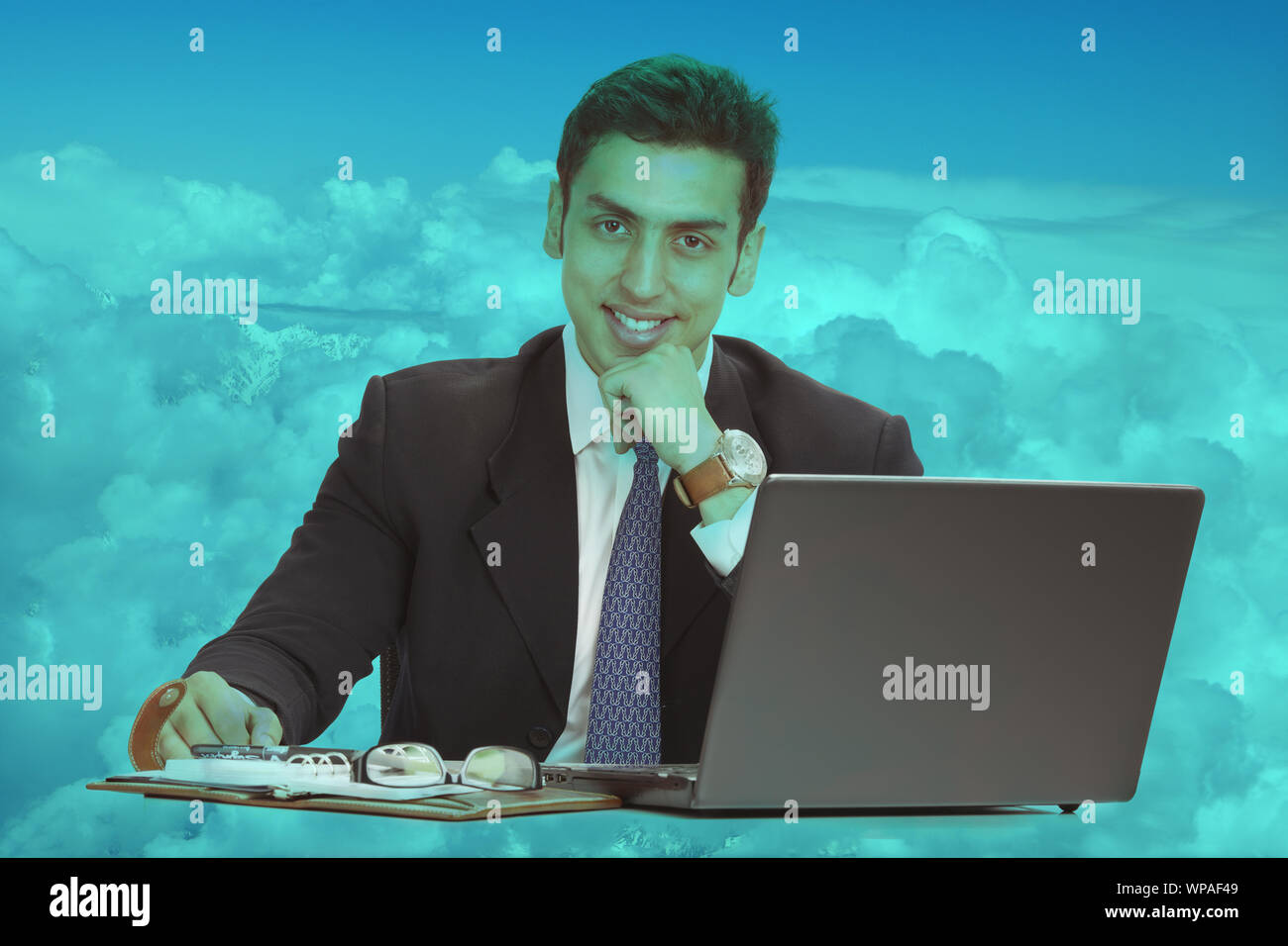 Young man sitting on clouds and using a laptop Stock Photo