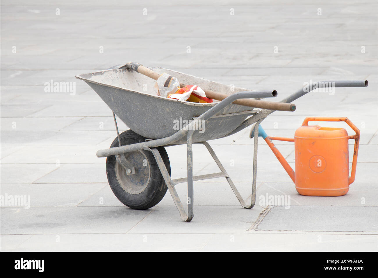 Wheelbarrow, shovel and bucket at street paving construction site Stock Photo