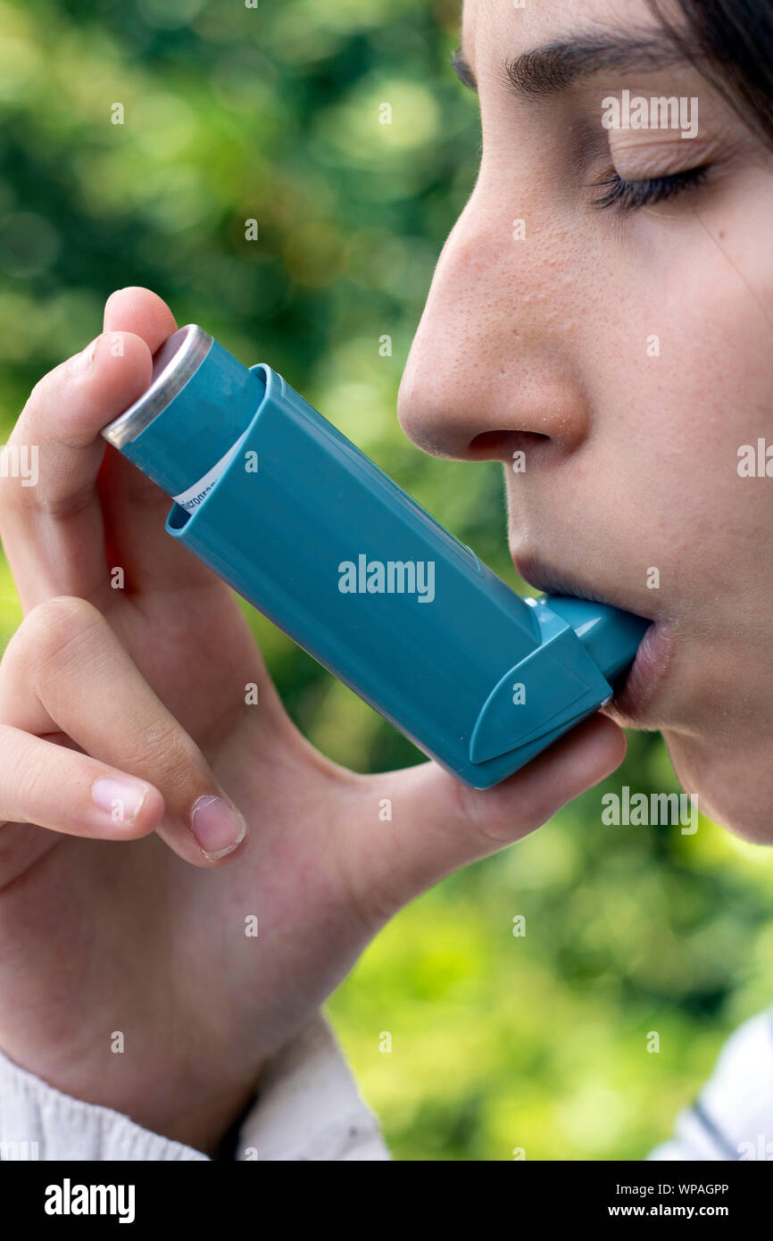 Health and medicine Young girl using blue asthma inhaler to prevent