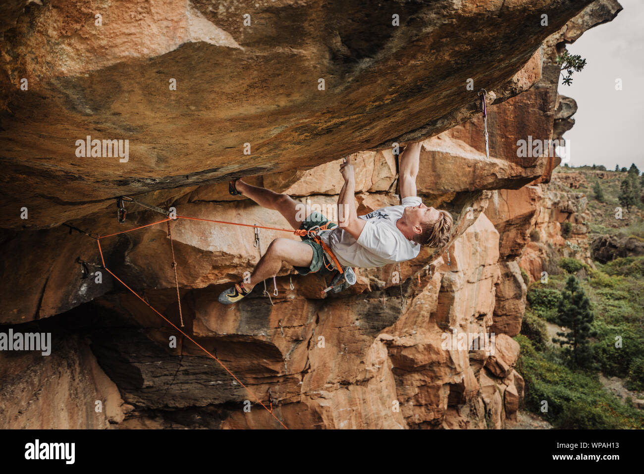 A young man climber lead climbing on an overhanging route Stock Photo
