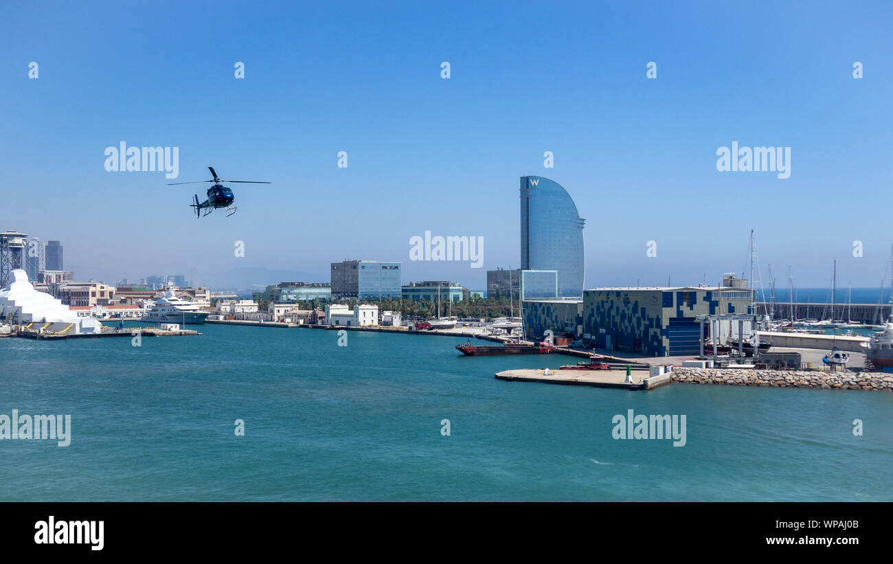 BARCELONA, SPAIN-MAY 9, 2019: Touristic helicopter (chopper) flying across Port Vell at the City Stock Photo