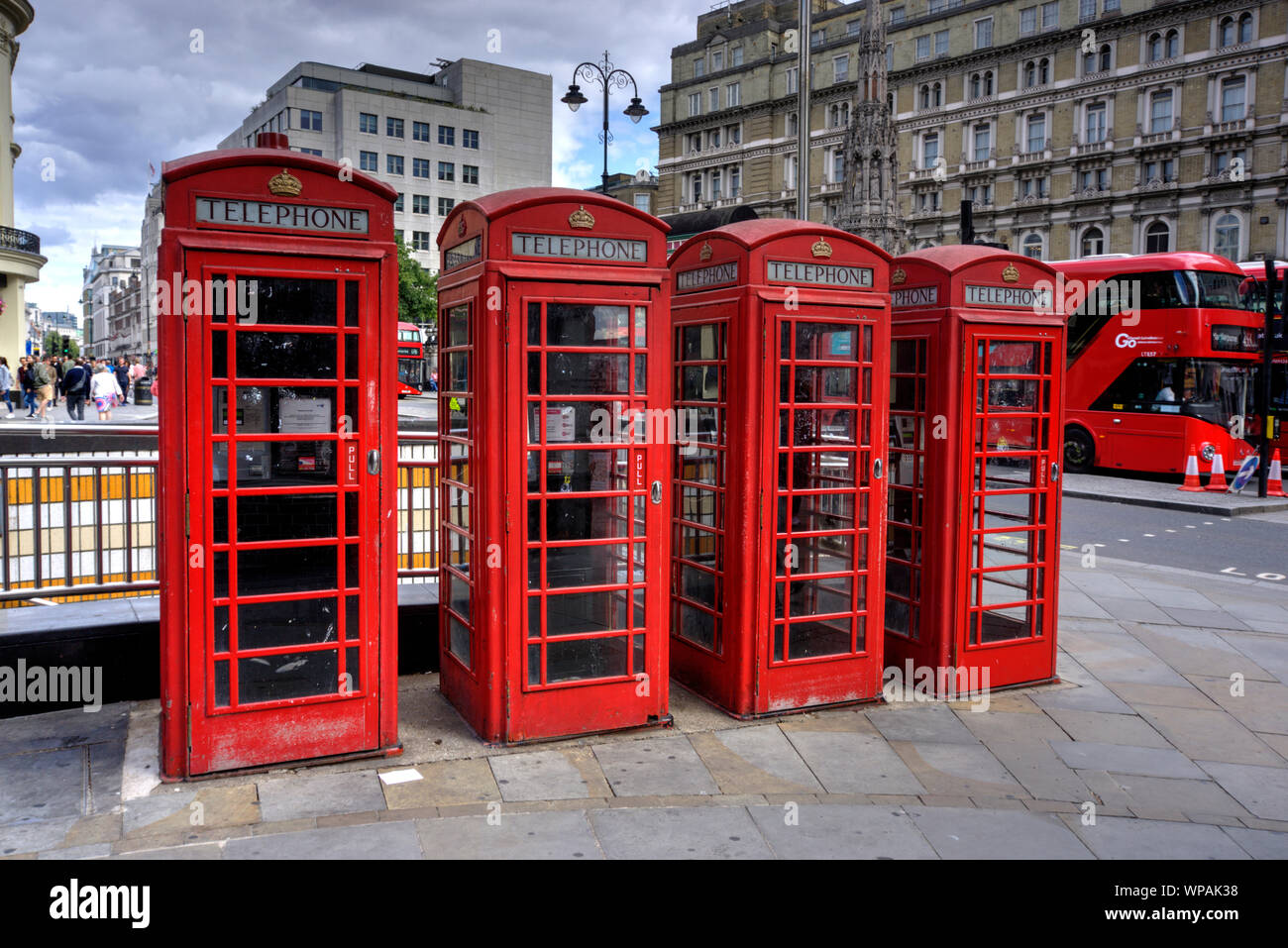 London, United Kingdom - September 7 15, 2019: Four iconic red telephone boxes in a row in Charing Cross central London with red buses in background Stock Photo