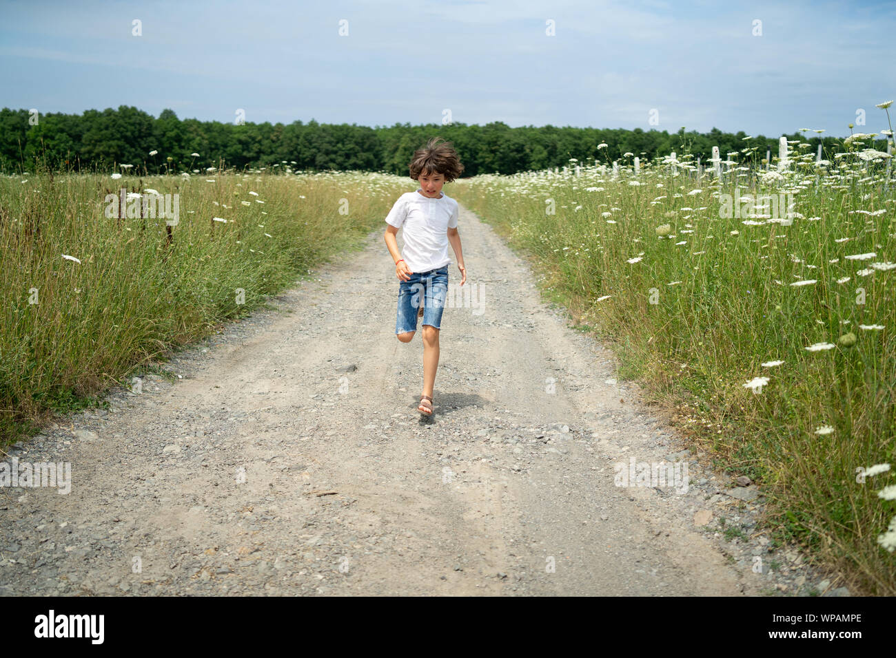 Scared boy in shorts and a tshirt runs along the road through the