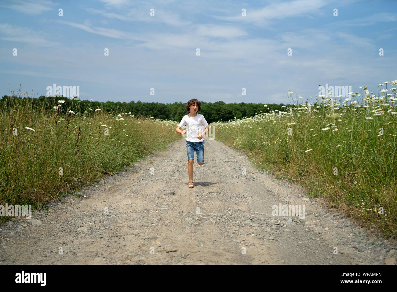 Scared boy in shorts and a tshirt runs along the road through the