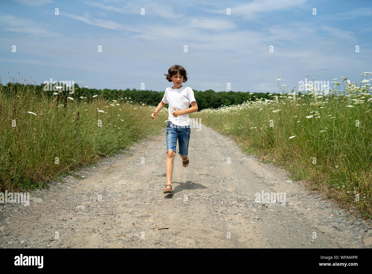 Scared boy in shorts and a tshirt runs along the road through the