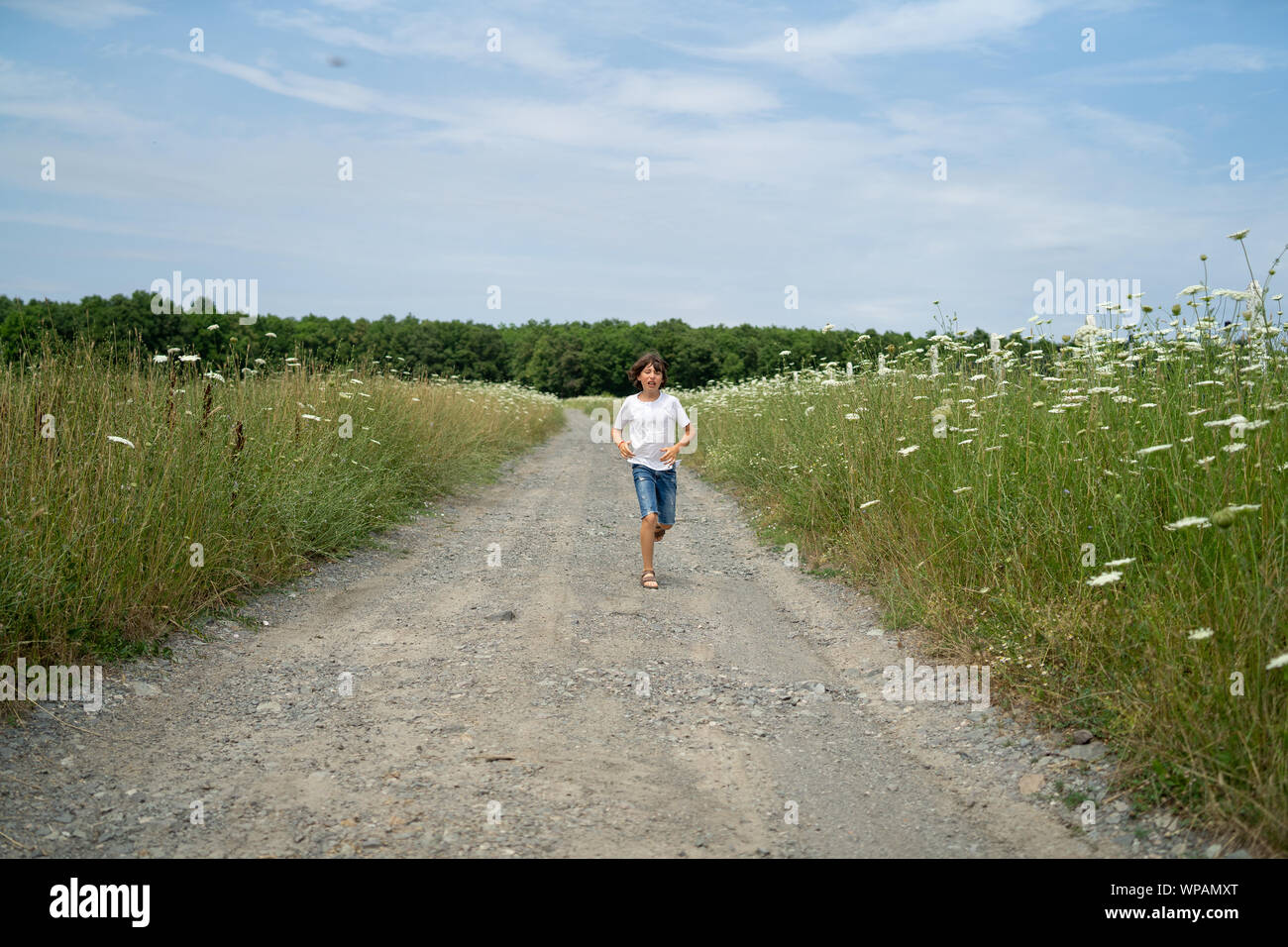 Scared boy in shorts and a tshirt runs along the road through the