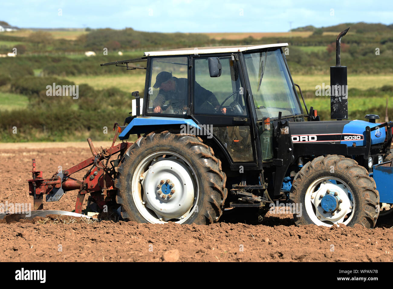 Farmer carefully watches his plow from cab of tractor to control the width, depth and uniformity of each plot of furrows in Gower Plowing Match Stock Photo