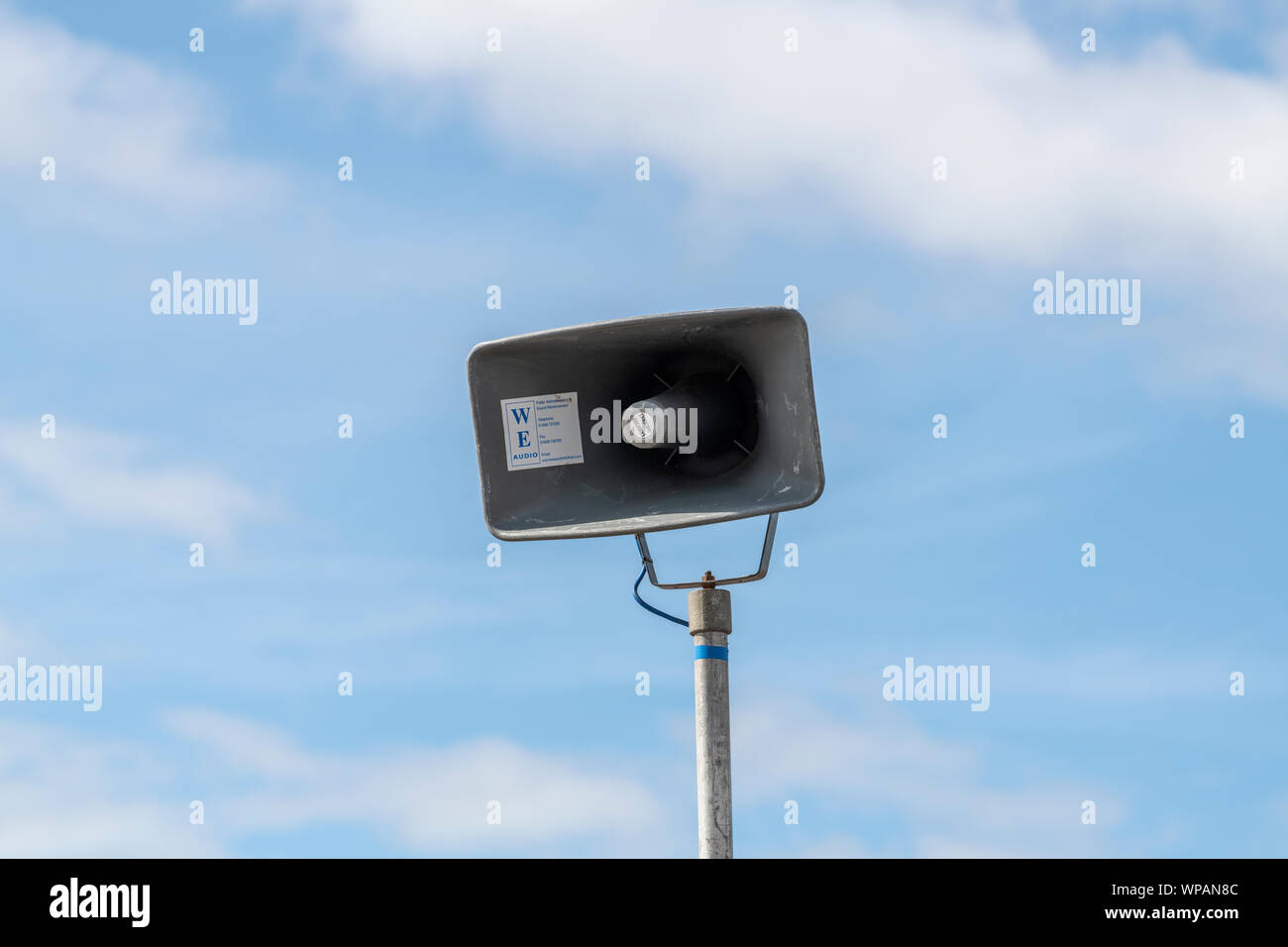 Public address system loudspeaker mounted on a pole and photographed against a blue sky Stock Photo