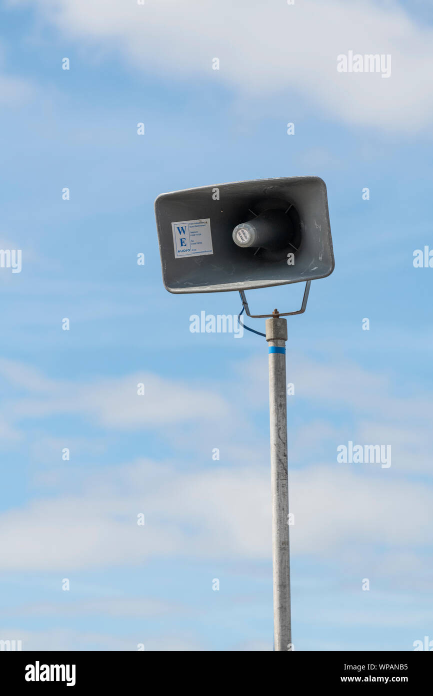 Public address system loudspeaker mounted on a pole and photographed against a blue sky Stock Photo