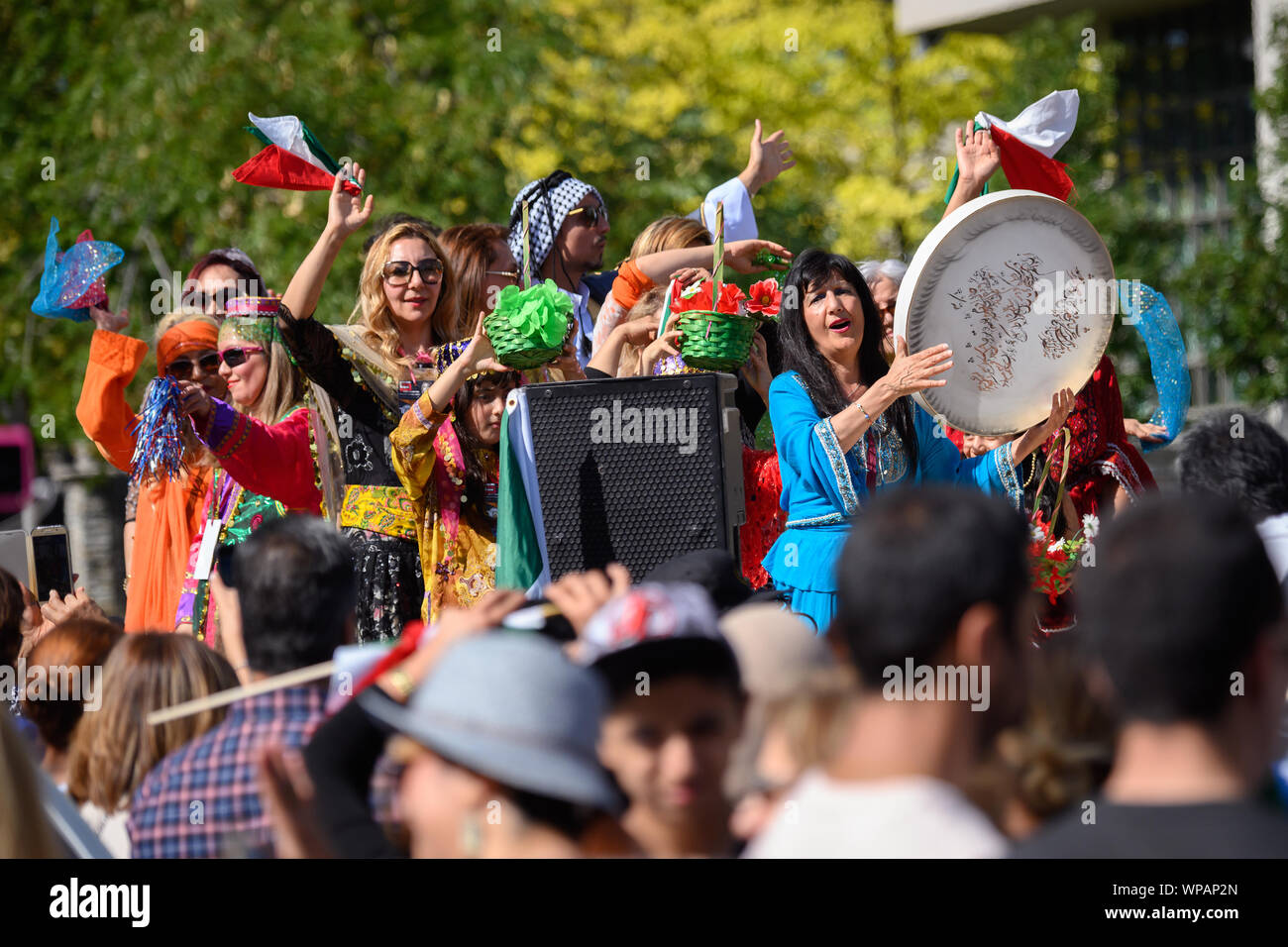 A float filled with people wearing traditional clothing proudly wave Lion and Sun flags from atop a float at the Top on Yonge Persian Parade. Stock Photo