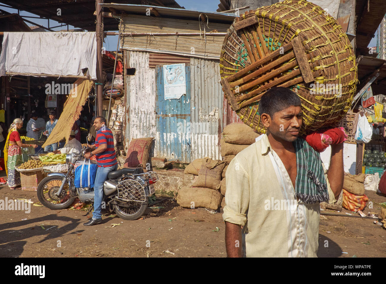 A porter with his basket stands ready to carry customers' purchased goods, at Byculla Market, a major fruit and vegetable market in Mumbai, India Stock Photo